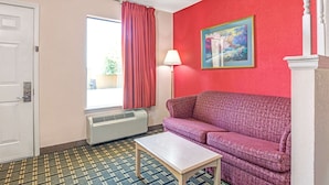 Ein Zimmer mit roter Wand, einem violetten Sofa, einer weißen Tür, einem Fenster mit roten Vorhängen, einer Fußbodenheizung und einem Gemälde.