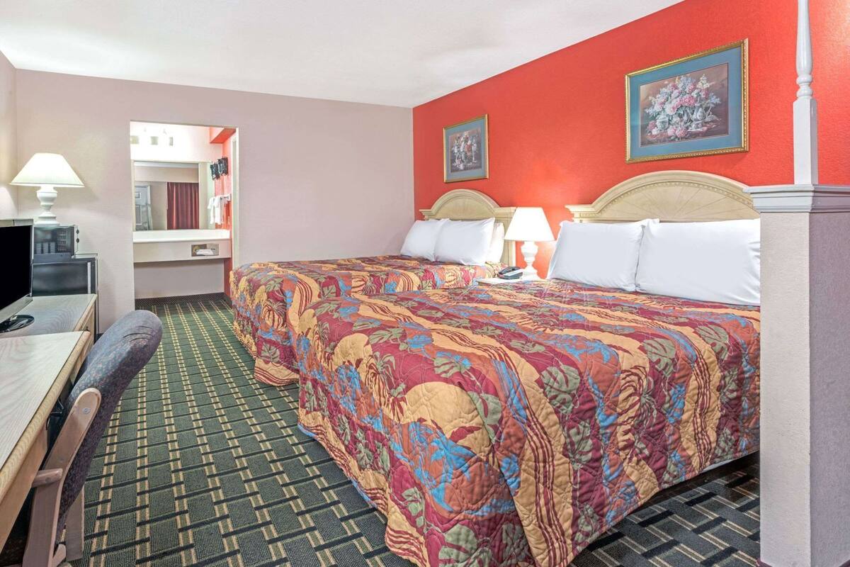 Ein Hotelzimmer mit einem Bett, einem Schreibtisch mit Computer, einem Sessel und einem Fernseher.