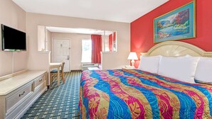 Ein Hotelzimmer mit einem großen Bett, einem Schreibtisch, einem Fernseher und einem Bild an der Wand.