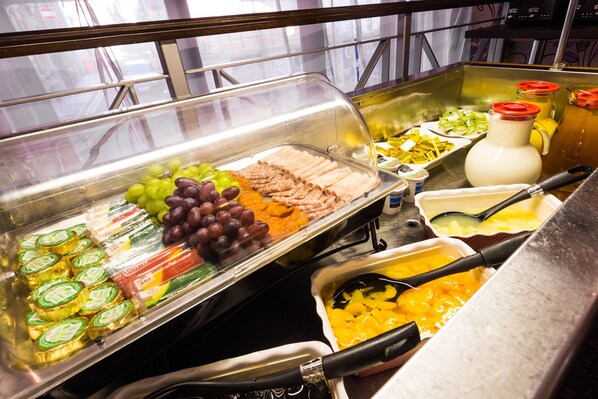 A buffet with various food items including fruits, cheeses, and sauces.