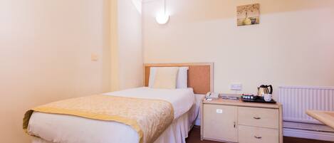 A hotel room with a bed, bedside table, and a small cabinet.