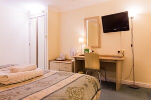 Una habitación de hotel con una cama, un escritorio, una silla, un televisor y una lámpara.