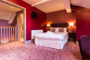Habitación de hotel con cama, dos lámparas de noche, televisor y una silla.