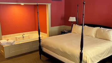 Una cama con dosel con edredón blanco, un ventanal grande y un baño con bañera y tocador.
