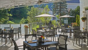 Un patio al aire libre con mesas, sillas, sombrillas y plantas en macetas.