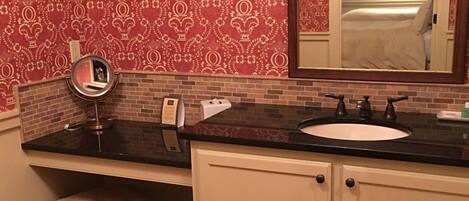 A bathroom with a black countertop, a white sink, and a mirror.