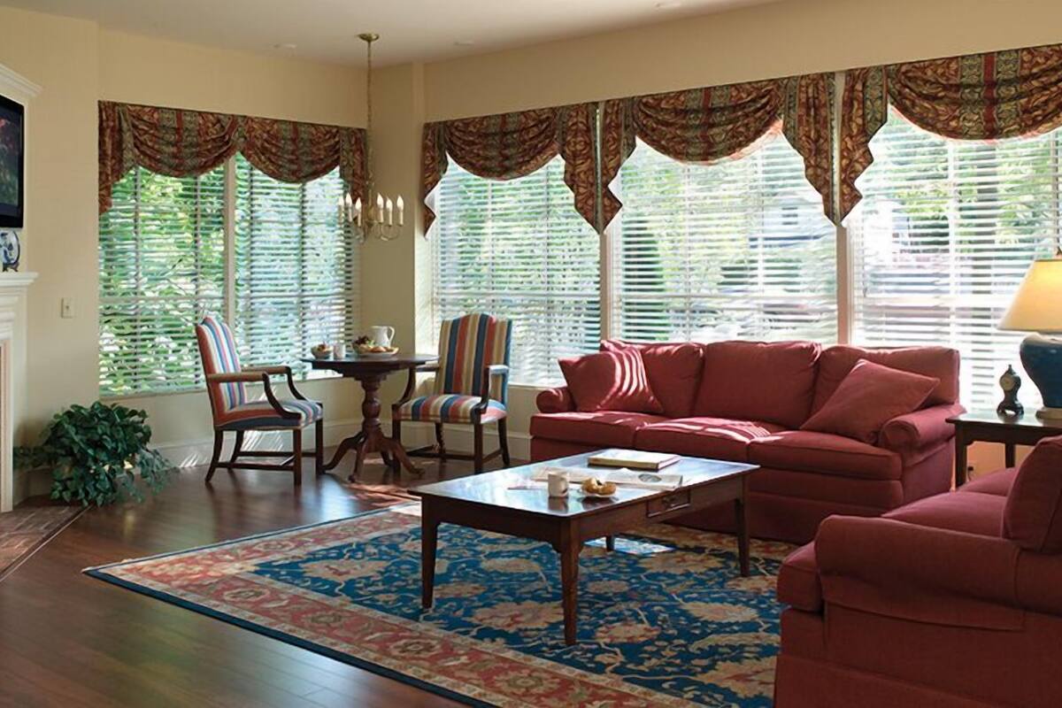 A living room with a fireplace, a red sofa, a coffee table, and a patterned rug.