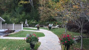 A stone pathway leading through a garden with potted plants and trees.