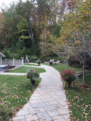 A stone pathway leading through a garden with potted plants and trees.