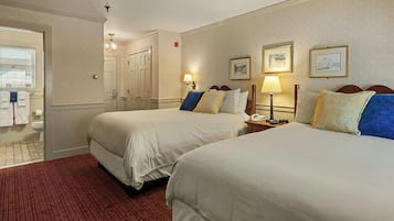 A hotel room with two beds, a bathroom, and a hallway.