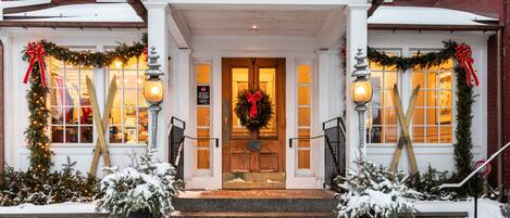 A hotel entrance with a wooden door, steps, and a porch.