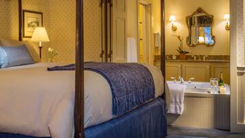 A hotel room with a large bed, a bathroom with a sink and mirror, and a door leading to another room.