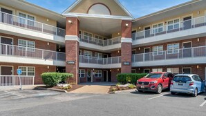 A multi-story hotel with a central lobby, multiple balconies, and a parking lot with cars. - Extended Stay America Suites Chesapeake Crossways Blvd (Chesapeake)