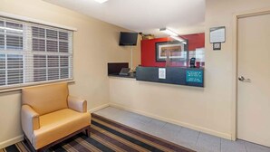 A reception area with a check-in counter, a sofa, a TV mounted on the wall, and a door. - Extended Stay America Suites Chesapeake Crossways Blvd (Chesapeake)
