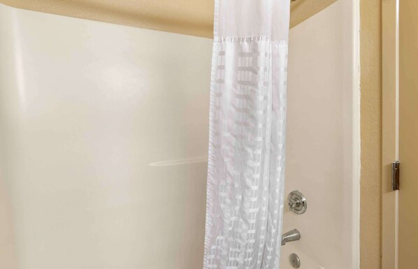 A bathroom with a white door, a silver handle, and a white shower curtain with a subtle pattern.