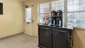 Una kitchenette con cafetera, microondas y dispensador de agua sobre una encimera.