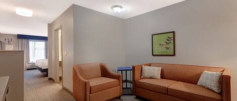A hotel room with a sofa, armchair, and a small table.