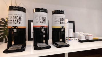 Three coffee dispensers labeled 'Decaf Roast,' 'Hot Water,' and 'Light Roast,' with coffee pods and cups on a counter.