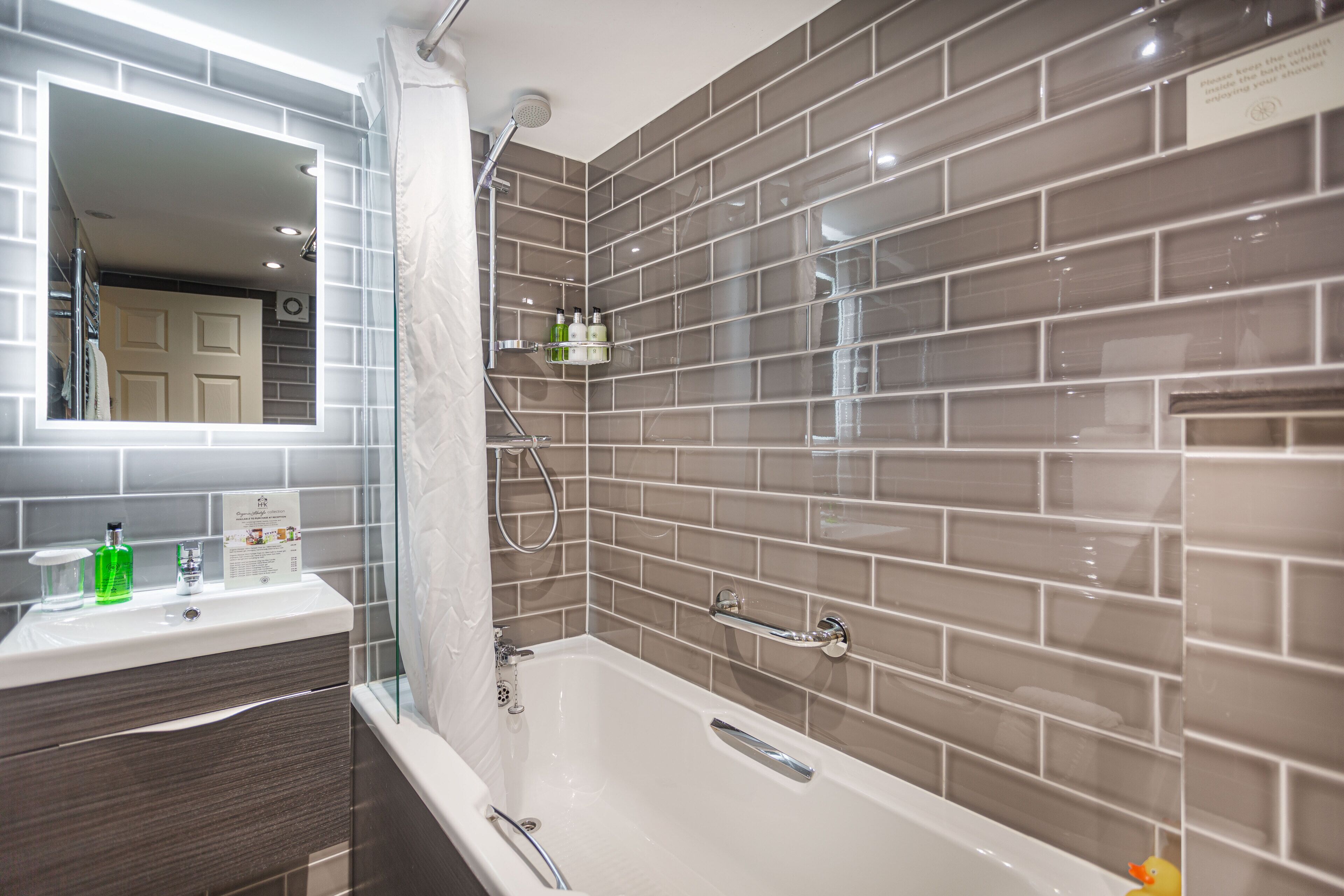 A modern bathroom with a bathtub, a vanity with a mirror, and a shower area.