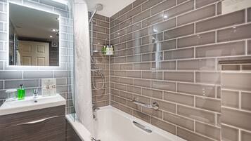 A modern bathroom with a bathtub, a vanity with a mirror, and a shower area.