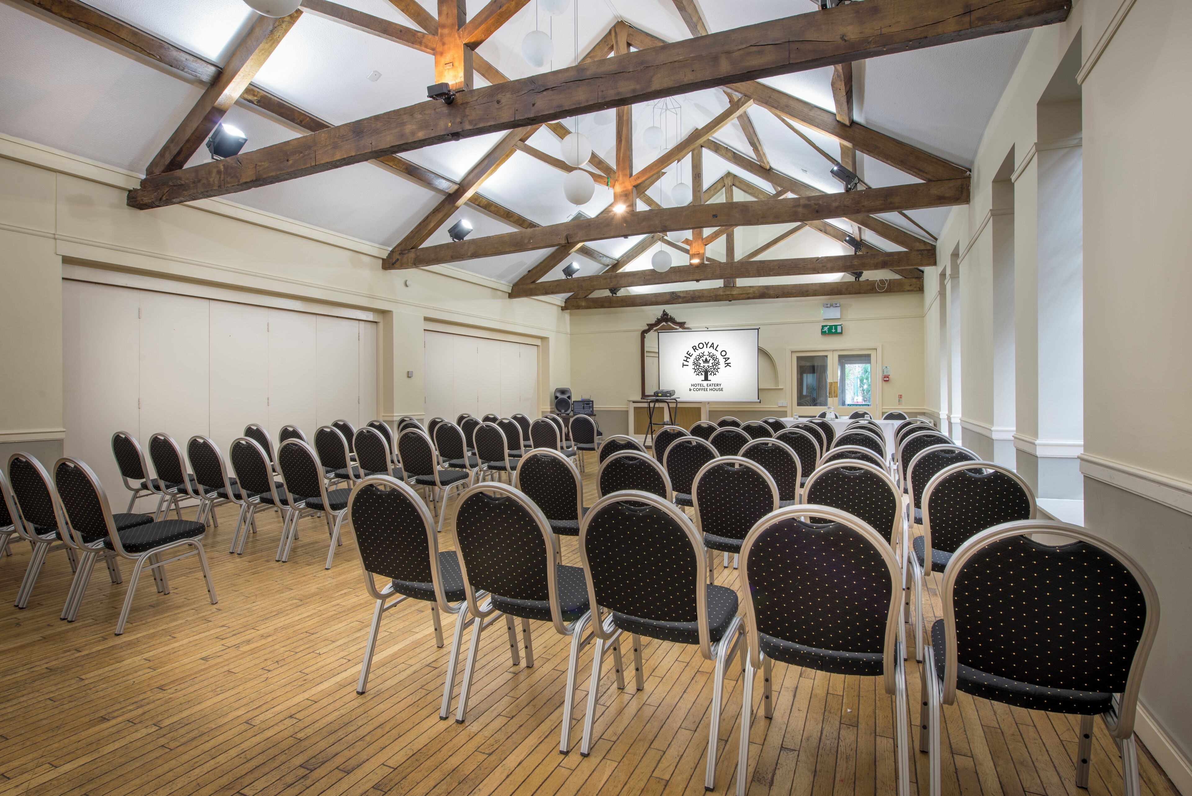 A conference room with a high ceiling, wooden beams, and rows of foldable chairs.