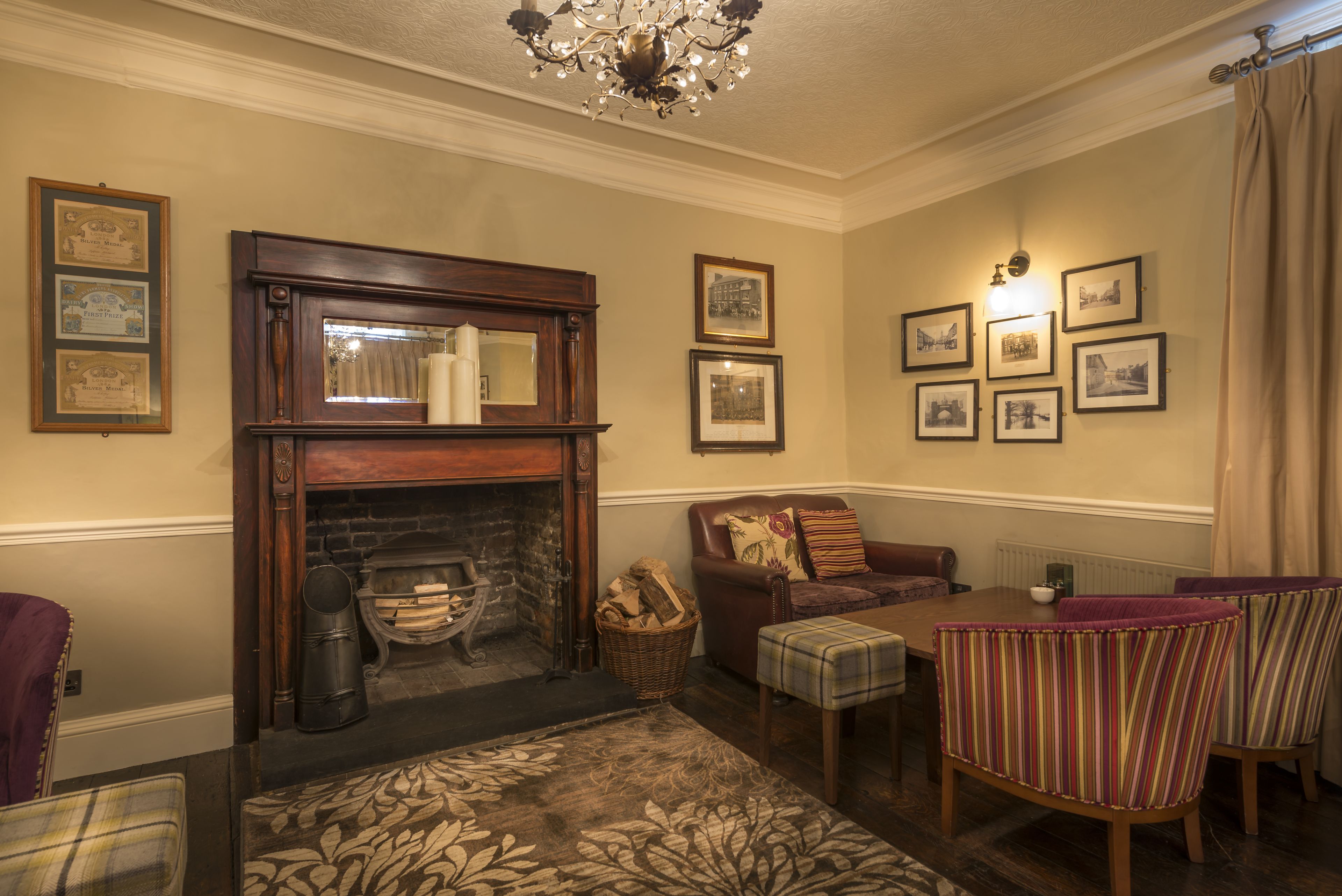 A cozy living room with a fireplace, a dining table, and several framed pictures on the walls.