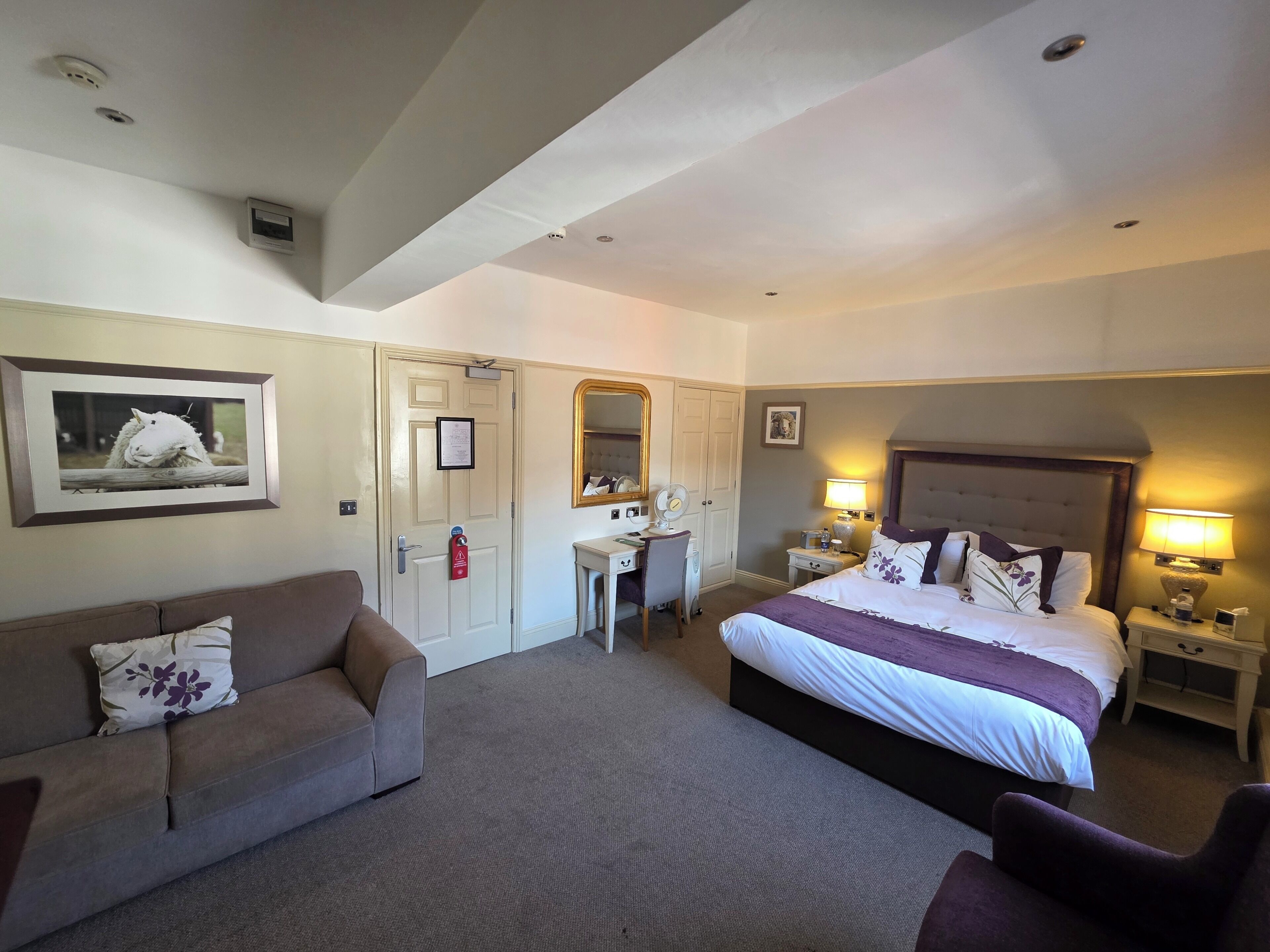 Una habitación de hotel con una cama, un escritorio, una silla, un sofá y un espejo.