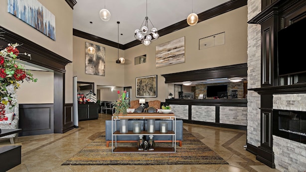 A spacious lobby with a central seating area, a fireplace, and a kitchen area in the background. - Best Western Windsor Suites (Fayetteville)