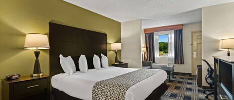 Habitación de hotel con una cama grande, dos mesitas de noche con lámparas, un escritorio con silla y vistas al exterior a través de la ventana.