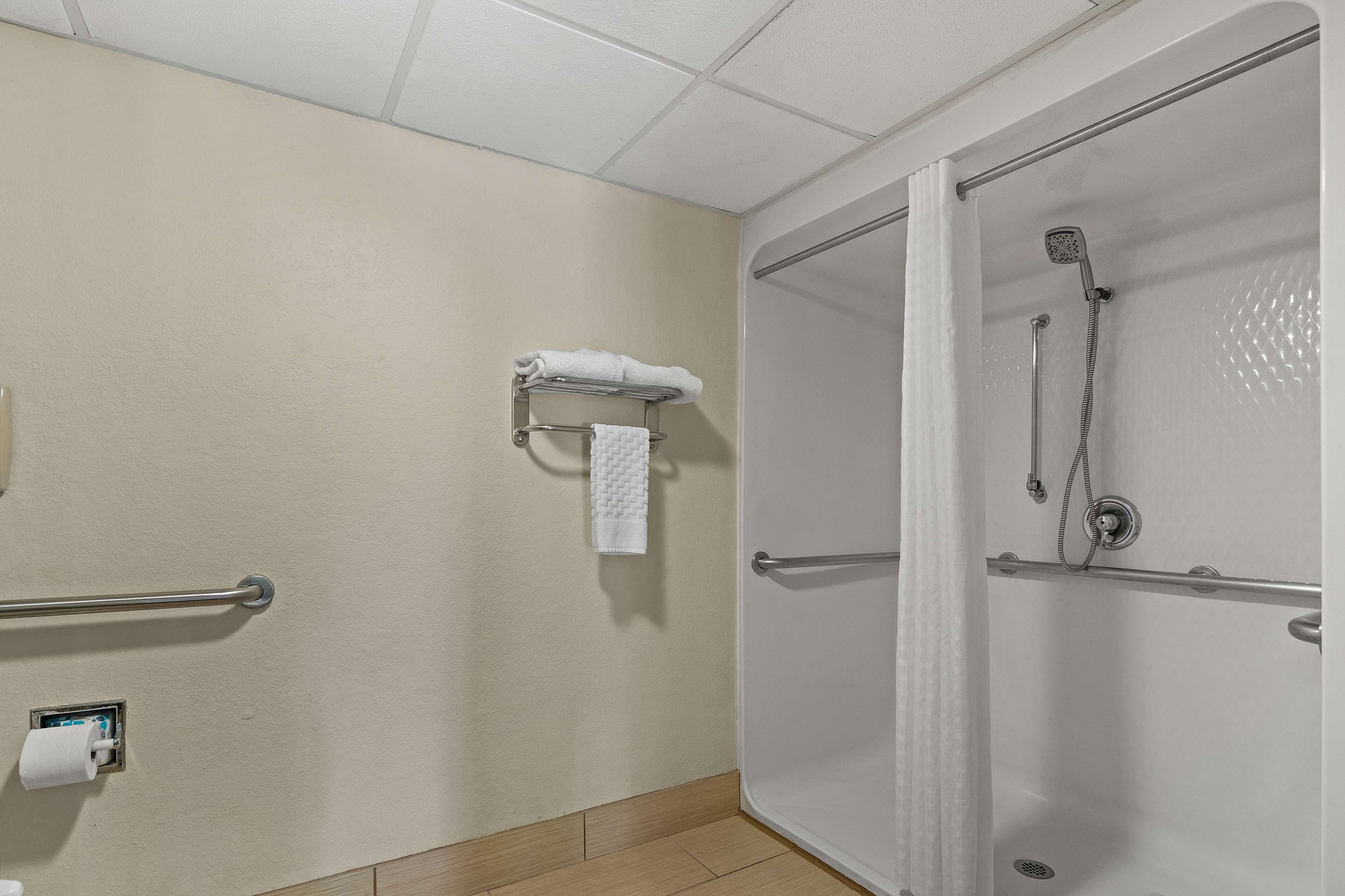 A bathroom with a shower, a towel rack, and a hand dryer.
