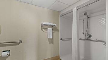 A bathroom with a shower, a towel rack, and a hand dryer.