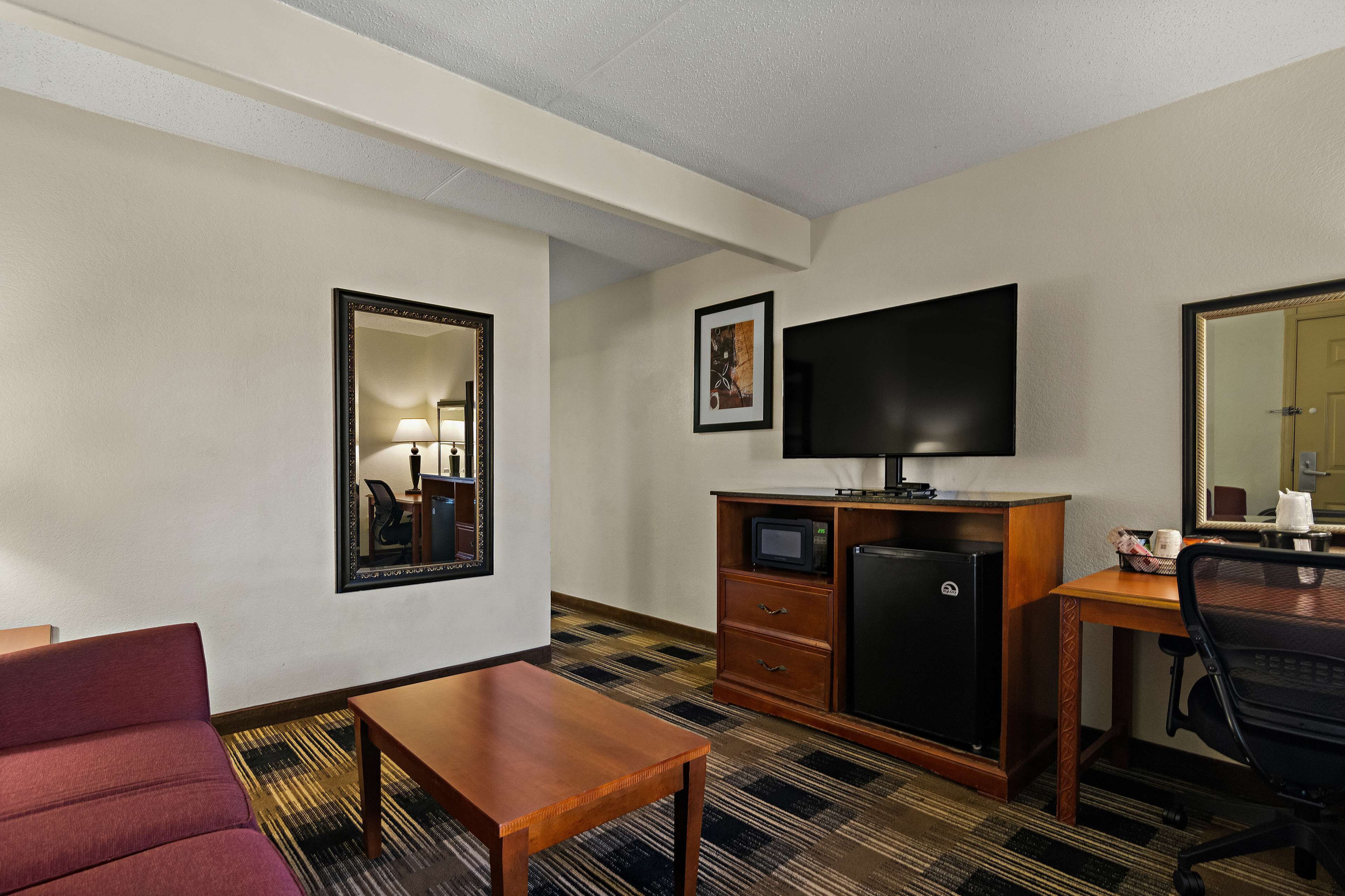 Une chambre d’hôtel équipée d’un lit, d’un bureau, d’une chaise, d’une télévision, d’un réfrigérateur et d’un four à micro-ondes.