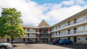 A multi-story hotel with a central entrance, parking lot, and several cars parked in front. - Extended Stay America Suites Virginia Beach Independence Blv (Virginia Beach)