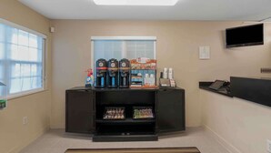 A room with a window, a flat-screen TV mounted on the wall, a coffee machine, and a shelf with snacks. - Extended Stay America Suites Virginia Beach Independence Blv (Virginia Beach)