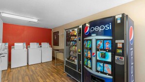 A room with a red wall, a white washing machine, a vending machine with Pepsi products, and a water dispenser. - Extended Stay America Suites Virginia Beach Independence Blv (Virginia Beach)