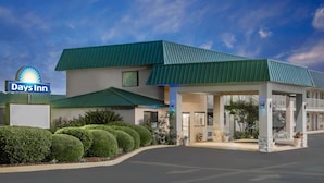 A Days Inn hotel with a green roof, a covered parking area, and well-maintained landscaping.