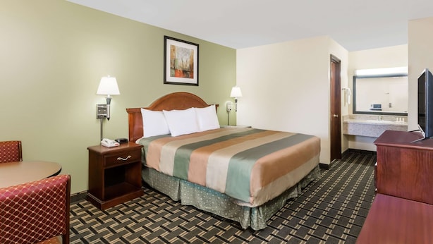 A hotel room with a bed, bedside lamps, a desk, and a chair.