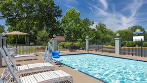 A pool area with lounge chairs, a fence, and a Days Inn sign.