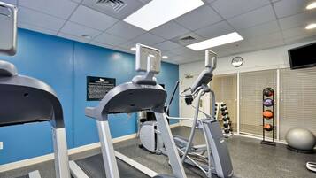 A fitness center with treadmills, an elliptical, and a set of dumbbells.