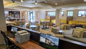 A modern hotel lobby with a reception desk, seating areas, and a view of the building. - Courtyard By Marriott Bentonville (Bentonville)