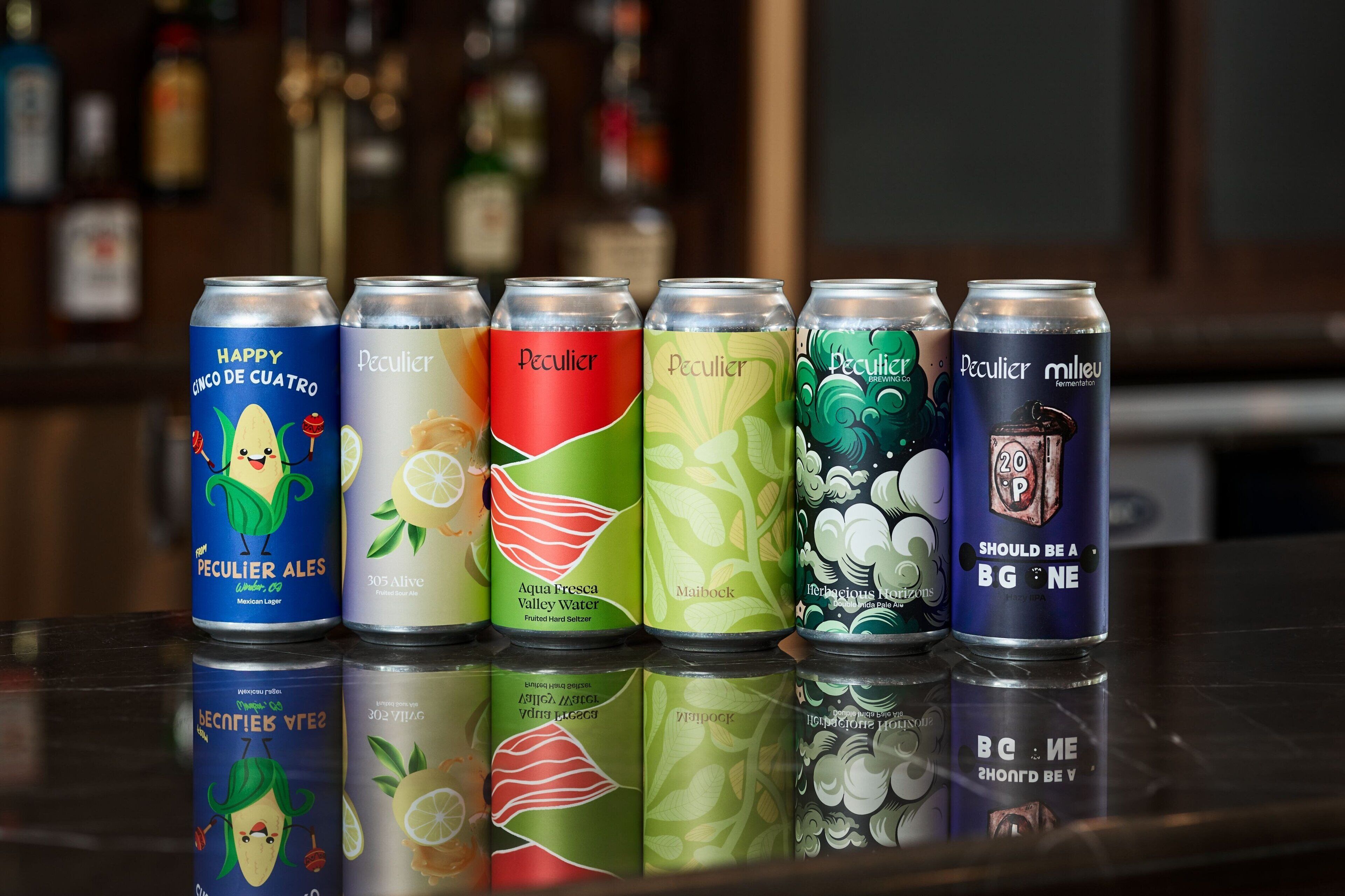 A row of beverage cans on a reflective surface.