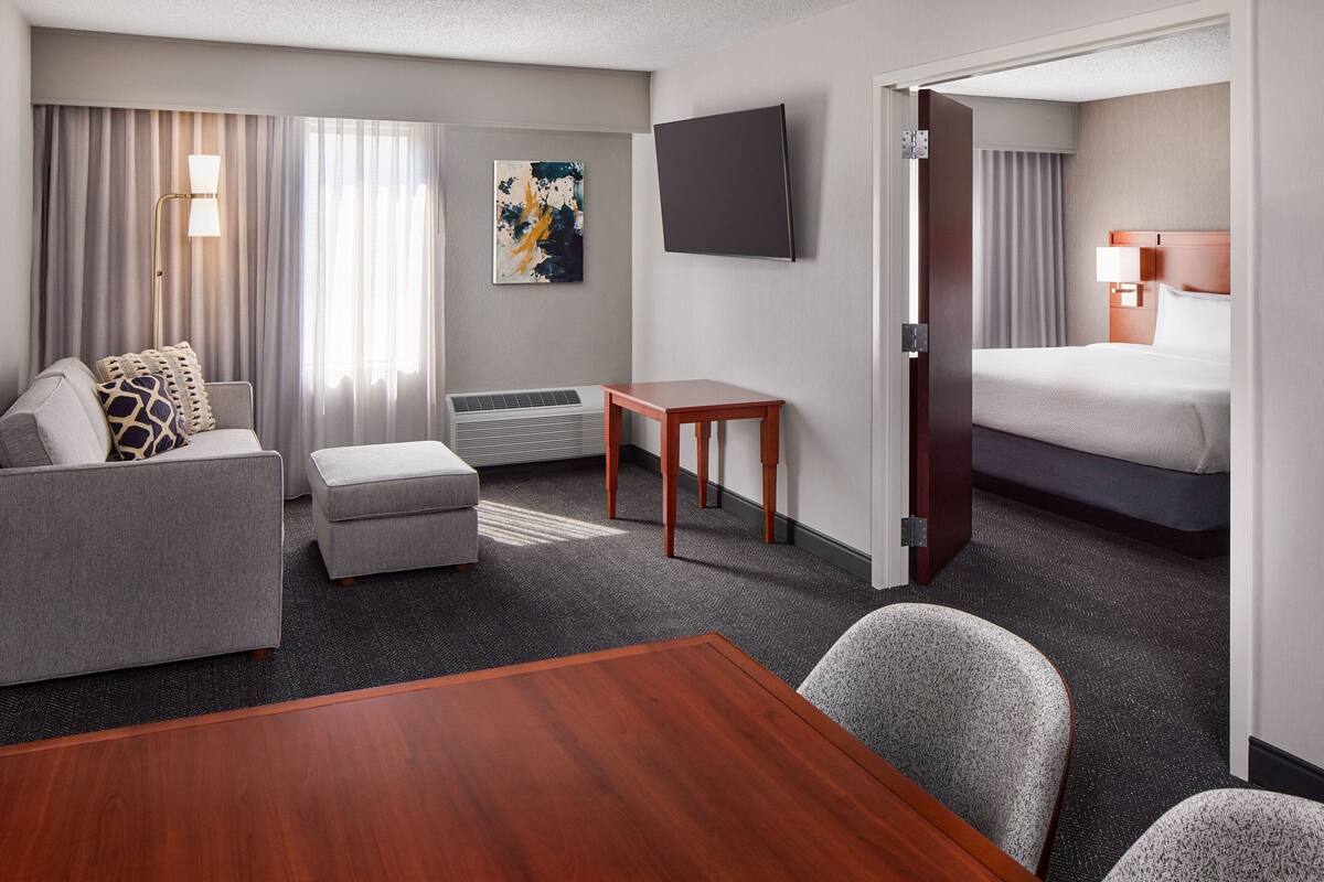 A hotel room with a bed, a sofa, a small table, and a TV.