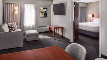 A hotel room with a bed, a sofa, a small table, and a TV.