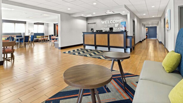 Een hotel lobby met een receptiebalie, zitgedeeltes en een gang.