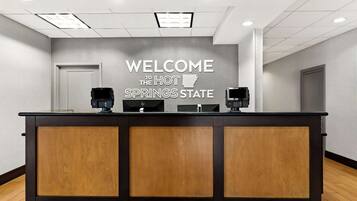 Una reception con un cartello che dice "WELCOME TO THE HOT SPRINGS STATE", due lettori di carte e un arredamento moderno.
