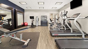 Een fitnessruimte met loopbanden, een hometrainer en krachtapparaten.