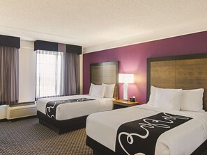 A hotel room with two beds, a nightstand with a lamp, a window with curtains, and a wall heater. - La Quinta Inn & Suites by Wyndham Denver Tech Center (Greenwood Village)