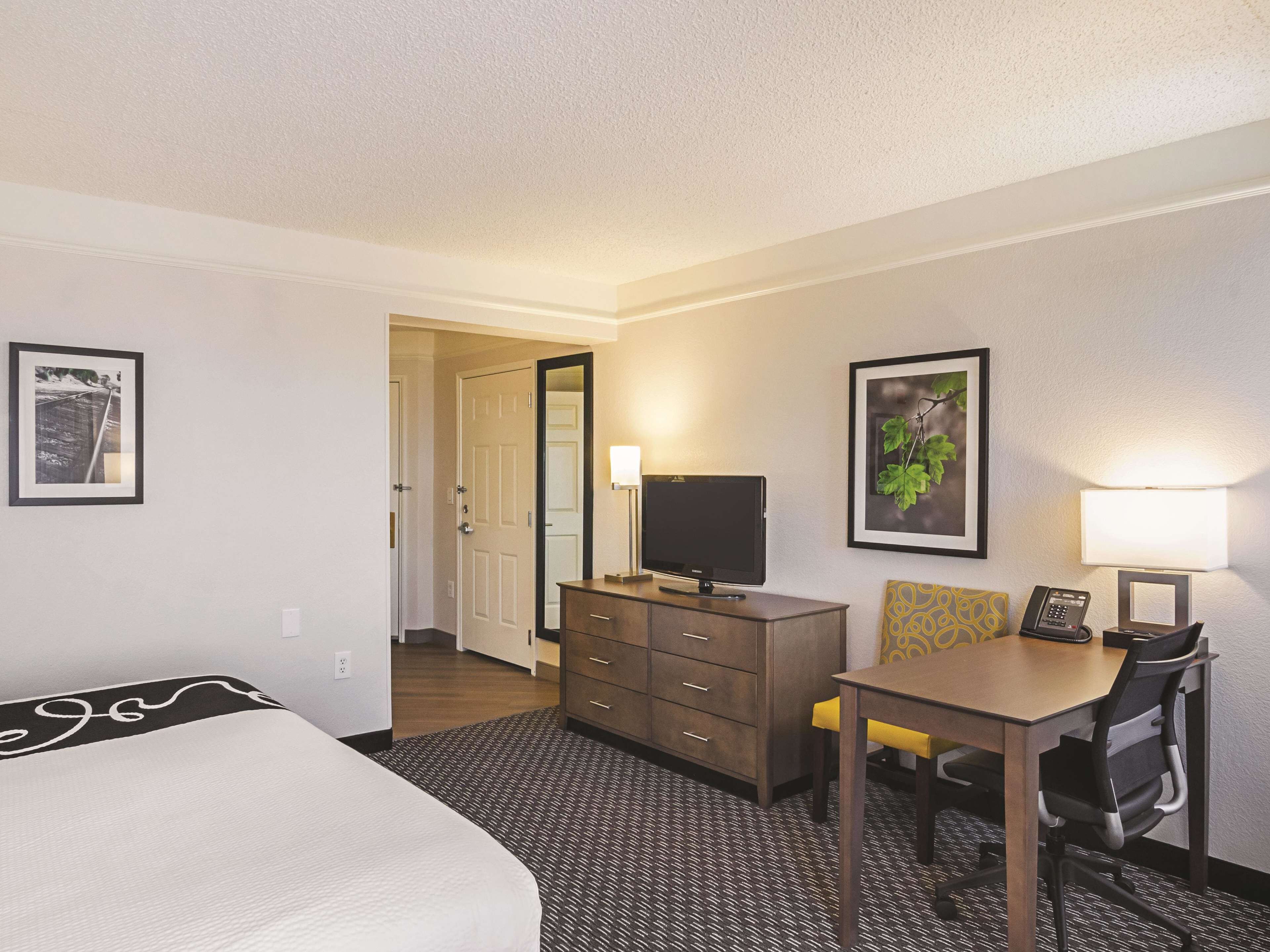 A hotel room with a bed, a desk with a chair, a television, and a telephone.