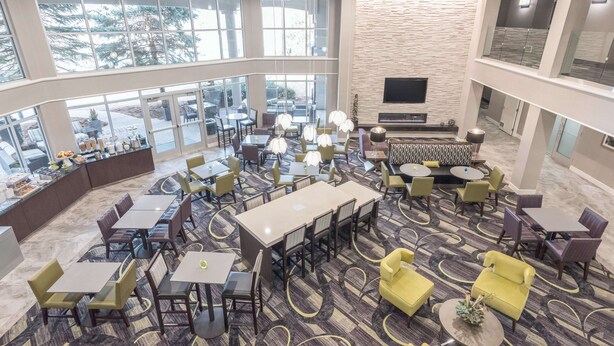 A spacious hotel lobby with multiple seating areas, a large TV screen, and a fireplace. - La Quinta Inn & Suites by Wyndham Denver Tech Center (Greenwood Village)