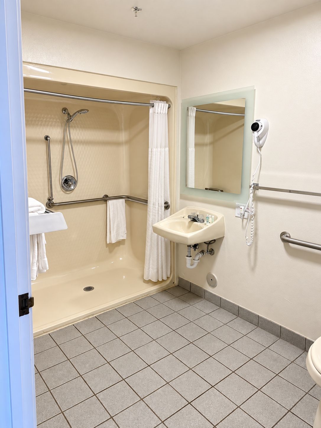 A bathroom with a walk-in shower, a sink with a mirror, and a toilet.